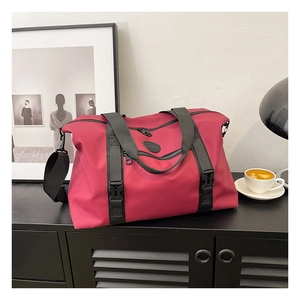 Detail of magenta travel bag with reinforced handles, shoulder strap and front zip pocket