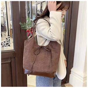 Detail of a brown suede tote bag with leather bow accent and spacious design for women