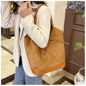 Detailed view of caramel suede tote bag styled with a beige blazer and blue denim jeans