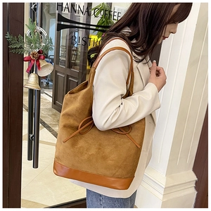 Detail of vintage brown suede tote bag with leather patchwork and ribbon bow decoration