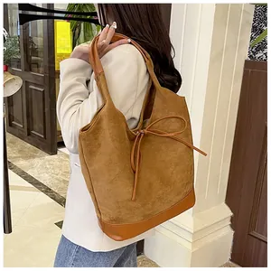 Detail of a brown tote bag with suede texture and a stylish leather bow decoration