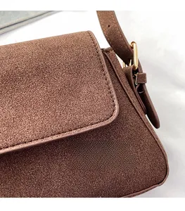 Close-up of brown suede baguette bag featuring precision stitching and metal buckle details