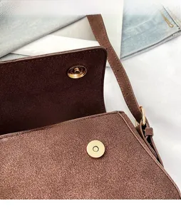 Close-up of golden magnetic snap closure and fine stitching on a brown suede bag