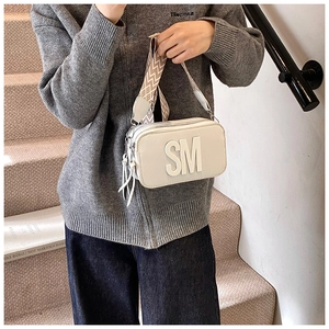 Detail of white leather crossbody bag with 3D SM logo and wide wavy shoulder strap