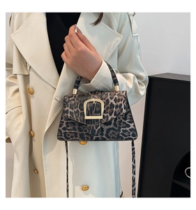Detail of vintage leopard print crossbody bag with large golden square buckle on white coat