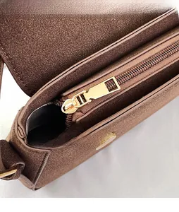 Macro shot of smooth gold zipper and layered interior of a brown matte suede bag