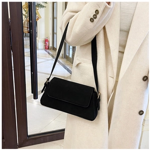 Minimalist black baguette shoulder bag with gold buckle on a model in daily life