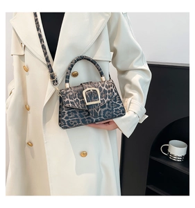 Detail of leopard print handbag with gold metal buckle and round handle on white coat