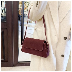Detail of burgundy frosted leather shoulder bag shown on model with gold hardware accents