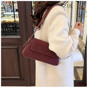 Detailed side view of deep burgundy suede baguette bag worn with a white wool coat