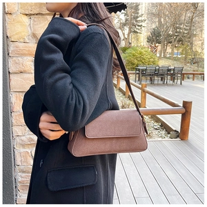 Close-up of retro brown shoulder bag in matte texture with elegant flap and slim strap
