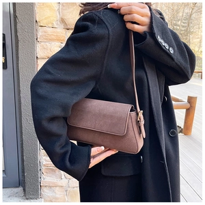 Detail of vintage brown suede baguette bag with gold hardware and slim strap