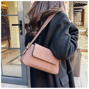 Detail of a brown matte suede shoulder bag with adjustable strap and vintage texture
