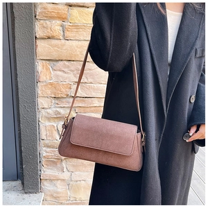 Detail of a brown matte suede shoulder bag with a rectangular flap and slim strap