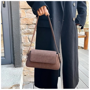 Detail of a brown matte suede shoulder bag featuring a rectangular flap and metal buckle