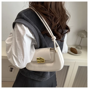 Detail of cream leather saddle bag with gold metal twist lock and knotted strap detail