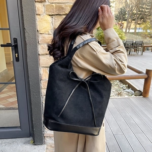 Minimalist large black tote bag with suede finish and leather bow accent on shoulder