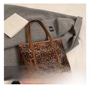 Detail shot of leopard print tote bag with brown leather accents and brand logo label