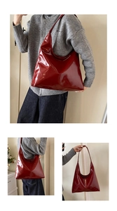 Macro detail of glossy dark red leather tote bag with wide shoulder strap and polished finish