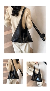 Detail of a black glossy patent leather large tote bag with wide shoulder strap design