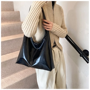 Close-up of a glossy black large tote bag made of high-quality PU leather with a sleek finish