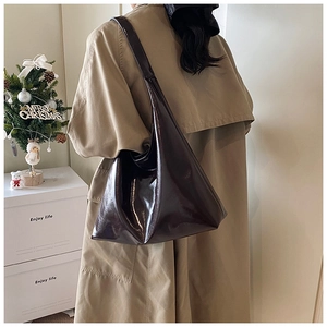 Primo piano di una borsa tote in vernice lucida abbinata a un elegante trench coat