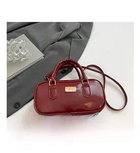 Primer plano de bolso rojo de charol brillante con placa dorada y asa metálica