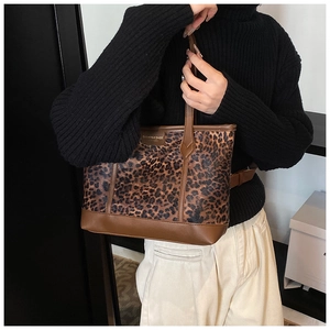 Close-up of leopard print tote bag featuring brown leather trim and fashion brand patch