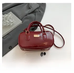 Detalle de un bolso de mano rectangular rojo con acabado pulido y decoración metálica
