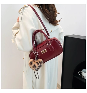 Detalle de bolso bandolera de cuero rojo oscuro con colgante de corazón de leopardo