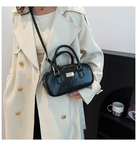 Bolso Boston vintage negro en cuero brillante combinado con una gabardina beige clásica
