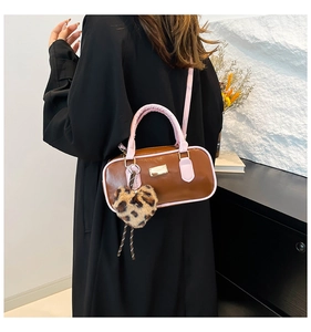 Detalle de bolso Boston en cuero PU marrón con toques rosas y colgante de corazón de leopardo