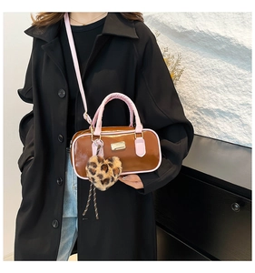 Bolso de hombro marrón charol con ribete rosa y colgante de corazón en una modelo