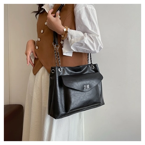 Detail of black pebbled leather crossbody bag with silver twist lock and chain strap