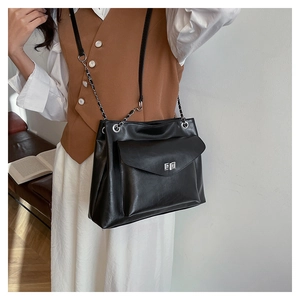 Close-up of black tote bag featuring a silver twist lock and chain strap on a model