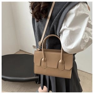 Detail of khaki tote bag with gold-tone hardware and adjustable shoulder strap on model