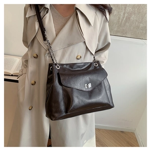 Deep brown faux leather tote bag with silver turn-lock and chain strap on a model