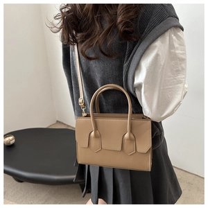 Brown leather tote bag worn as a crossbody by a model in a minimalist modern setting