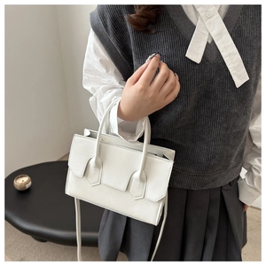 Detail of white minimalist crossbody bag showing high-quality leather texture and flap design