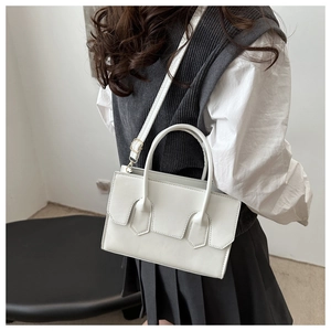 Lifestyle shot of white minimalist crossbody bag with gold hardware and top handle