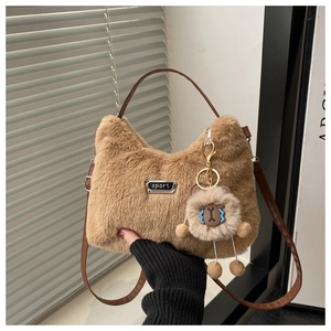Detail der braunen Plüschtasche mit Metall-Logo und süßem Bärenanhänger-Verzierung