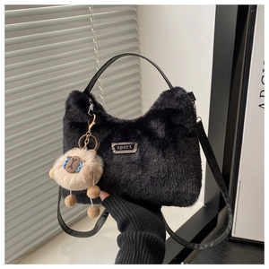 Nahaufnahme der schwarzen Plüschtasche mit Metallemblem und niedlichem Anhänger