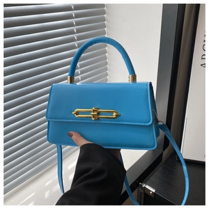 Detail view of bright blue crossbody bag featuring a golden metal lock and smooth texture