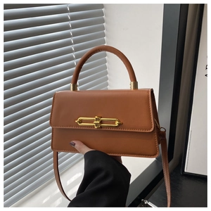 Detail of caramel leather shoulder bag with sleek gold bar buckle and fixed top handle