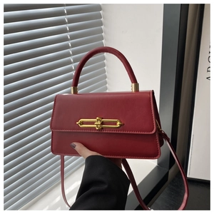 Detailed shot of a red leather handbag with elegant gold metal lock and leather handle