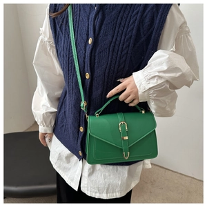 Detailed view of bright green faux leather crossbody bag with gold buckle on a model