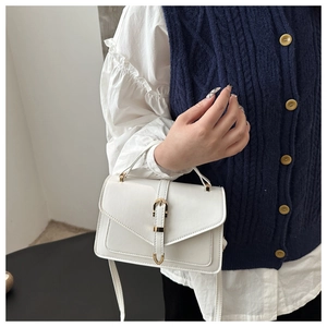 Detail of white leather handbag with golden buckle and V-shaped flap on blue vest