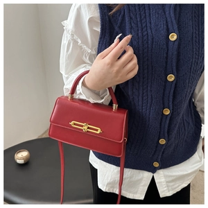 Detail of red leather square bag featuring elegant golden metal clasp and crossbody strap