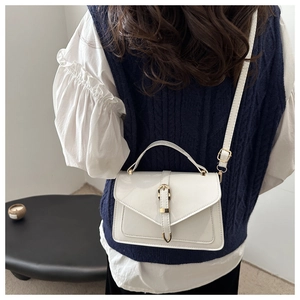 Detail of white glossy patent leather crossbody bag with elegant gold buckle hardware