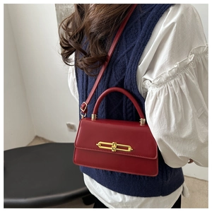 Model wearing a vintage red leather crossbody bag with gold metal buckle and top handle